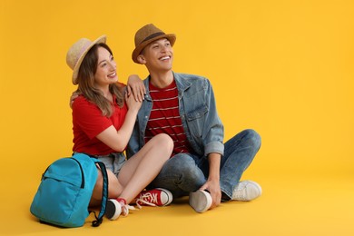 Photo of Happy travellers with backpack on yellow background. Space for text