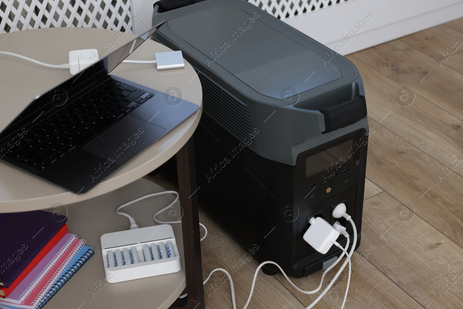 Photo of Modern portable power station, charging attached devices indoors