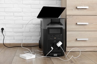 Photo of Modern portable power station, charging attached devices indoors