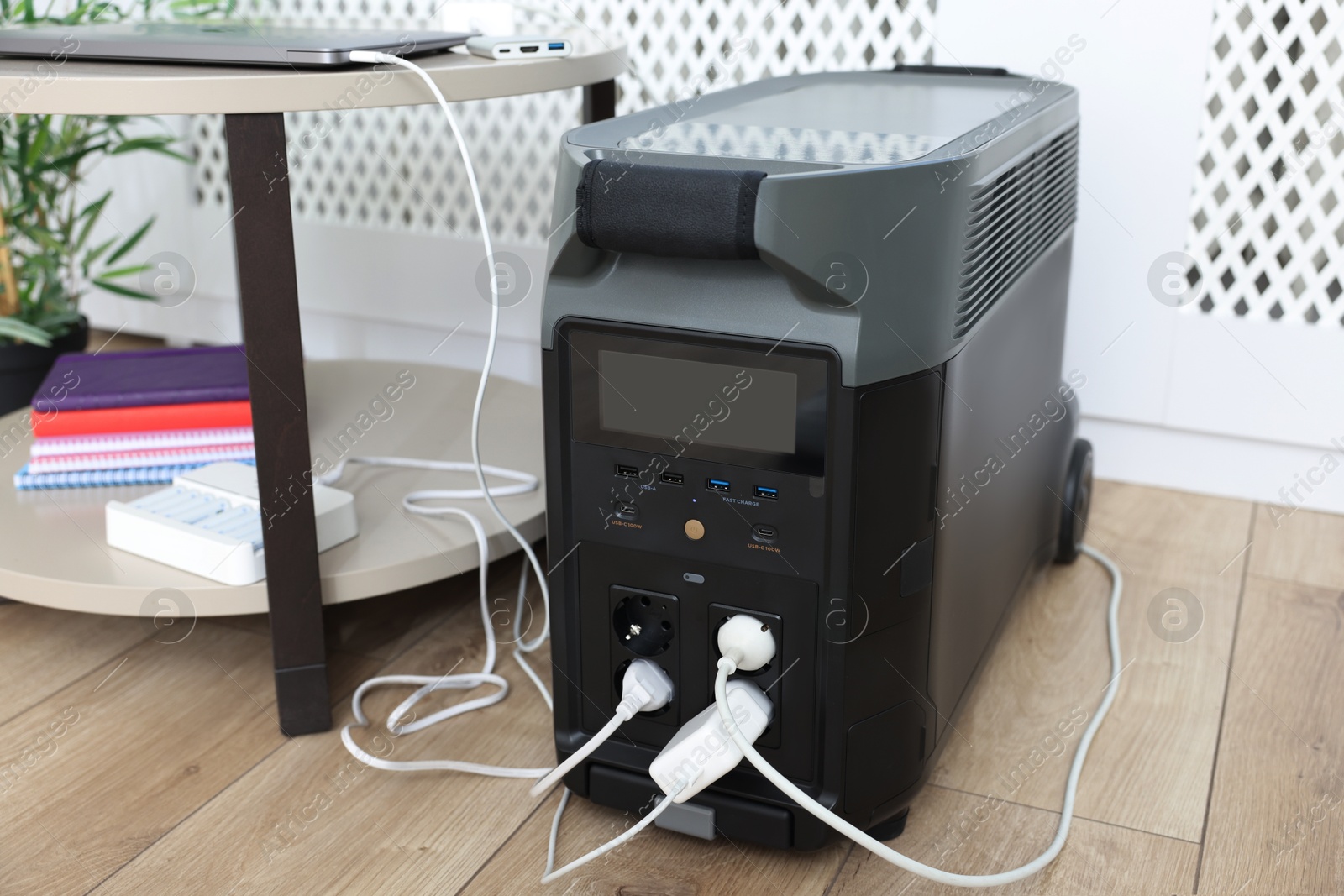 Photo of Modern portable power station, charging attached devices indoors