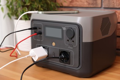 Photo of Smartphone charging from portable power station on wooden desk