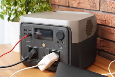 Photo of Portable power station with chargers on wooden desk indoors