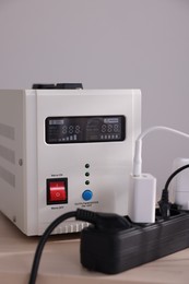 Photo of Portable power station and multi-socket extension board with chargers on table indoors