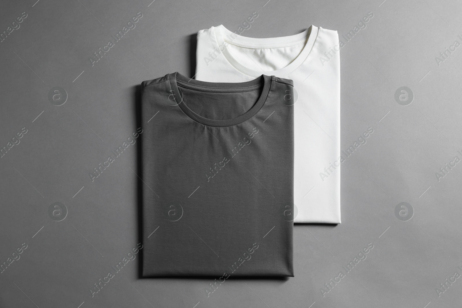 Photo of Different blank t-shirts on grey background, top view. Mockup for design