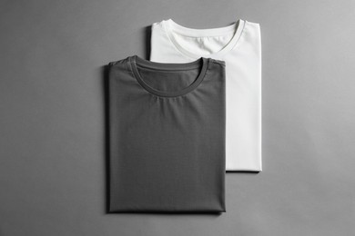 Different blank t-shirts on grey background, top view. Mockup for design