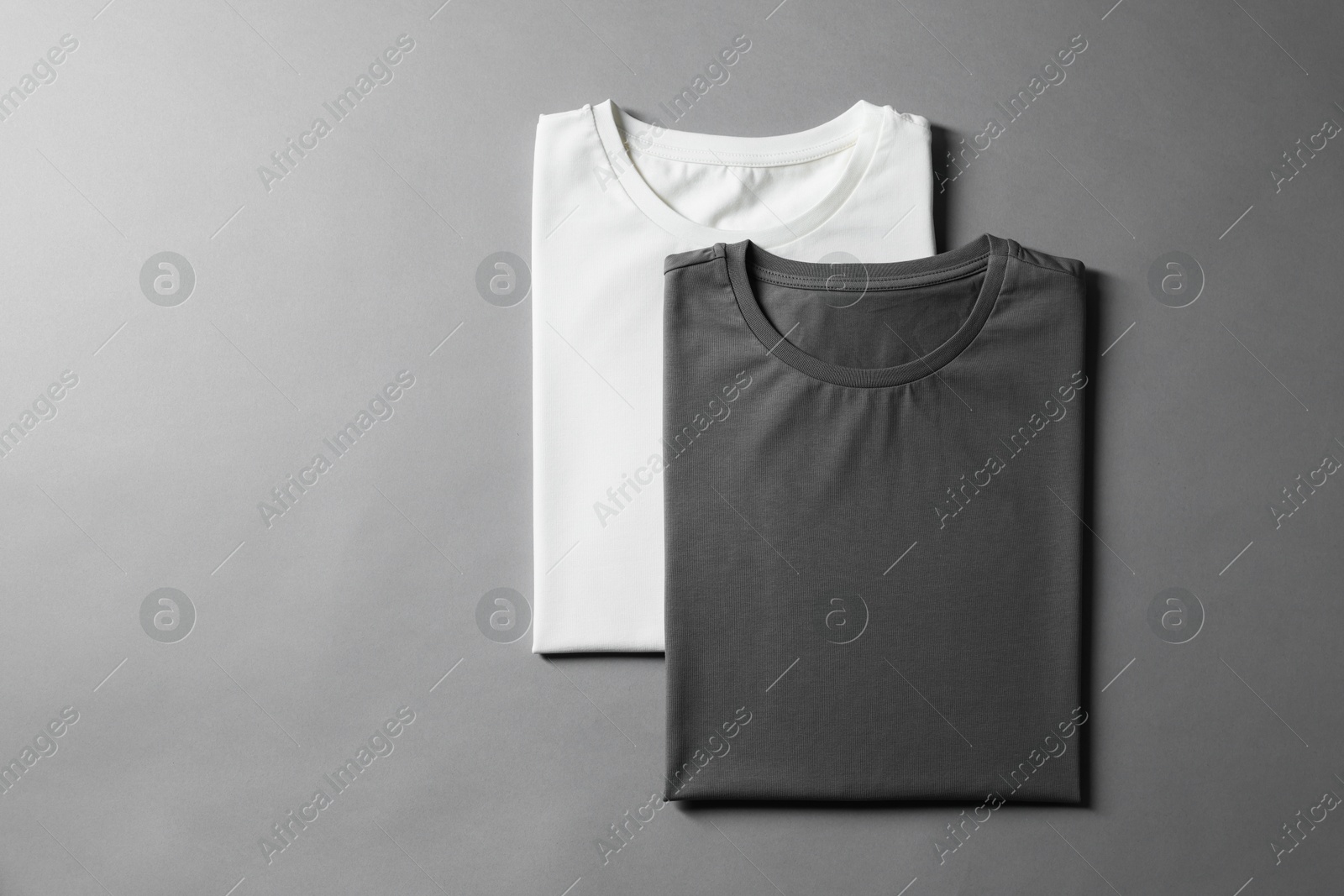 Photo of Different blank t-shirts on grey background, top view. Mockup for design