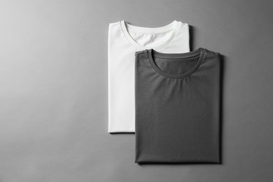 Different blank t-shirts on grey background, top view. Mockup for design