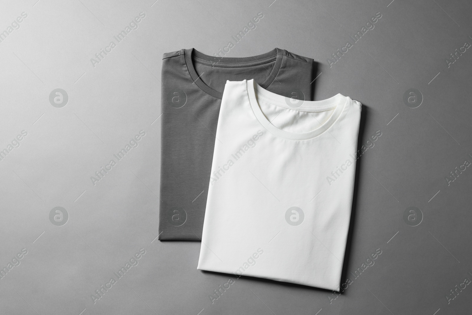 Photo of Different blank t-shirts on grey background, top view. Mockup for design