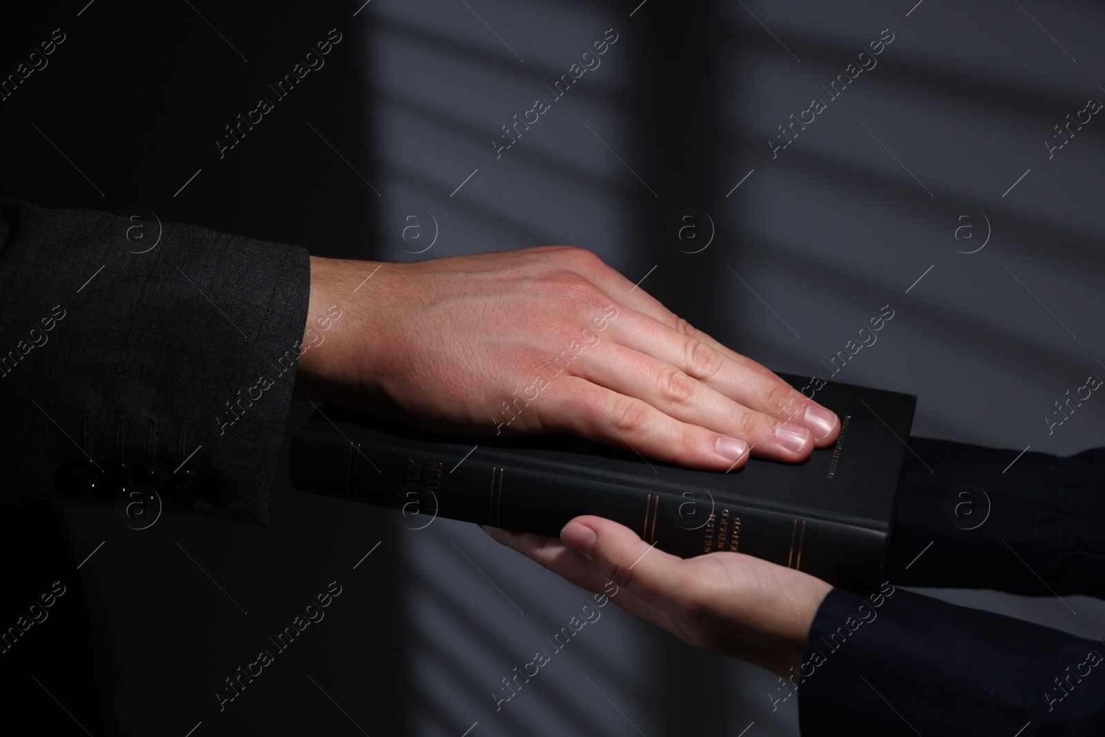 Photo of Man taking oath with his hand on Bible indoors, closeup