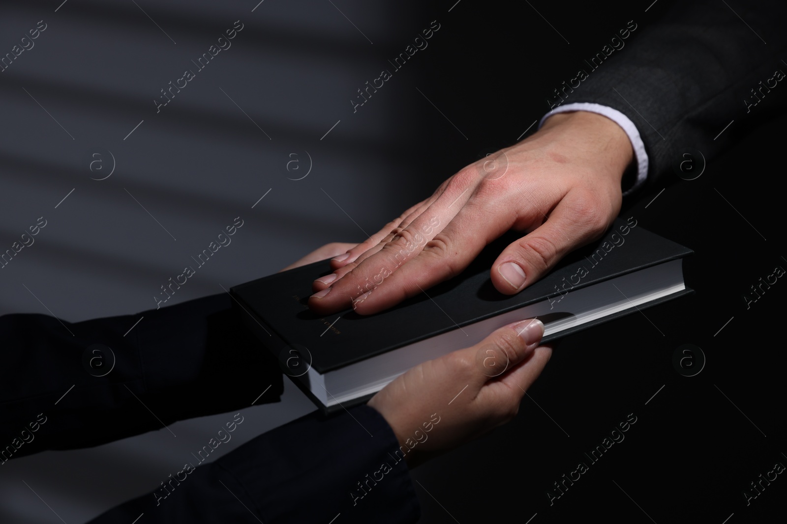 Photo of Man taking oath with his hand on Bible indoors, closeup