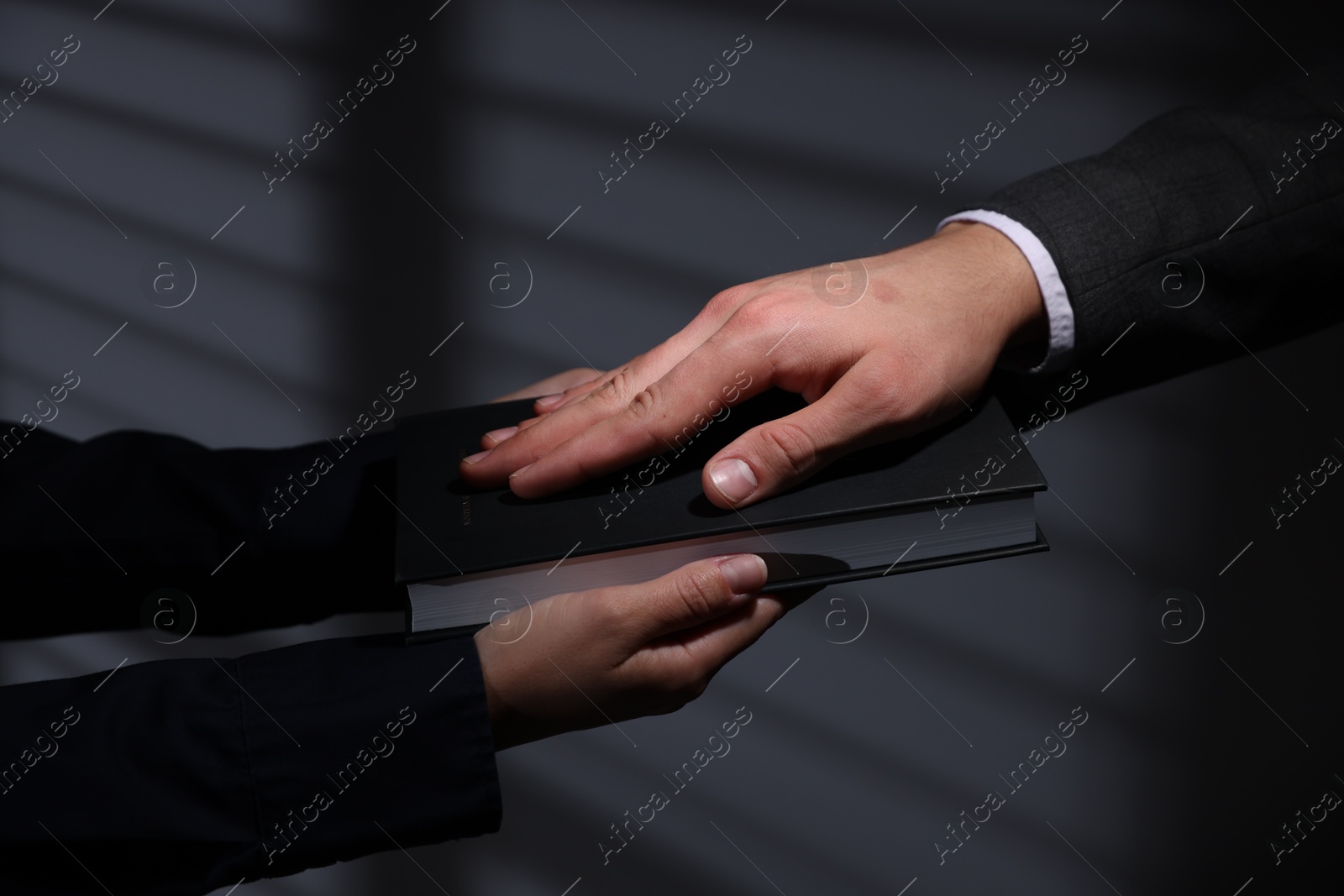 Photo of Man taking oath with his hand on Bible indoors, closeup