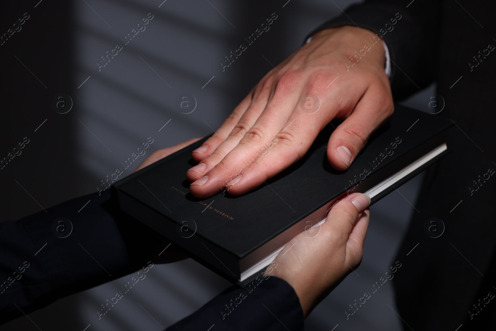 Photo of Man taking oath with his hand on Bible indoors, closeup