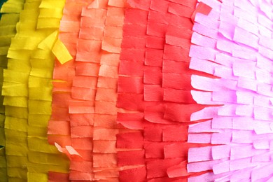 Photo of Pinata. Cut tissue paper in different colors as background, closeup