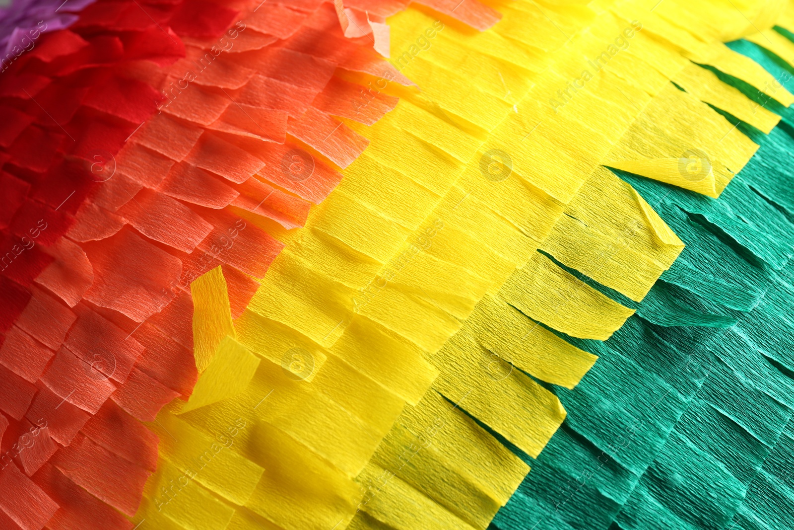 Photo of Pinata. Cut tissue paper in different colors as background, closeup