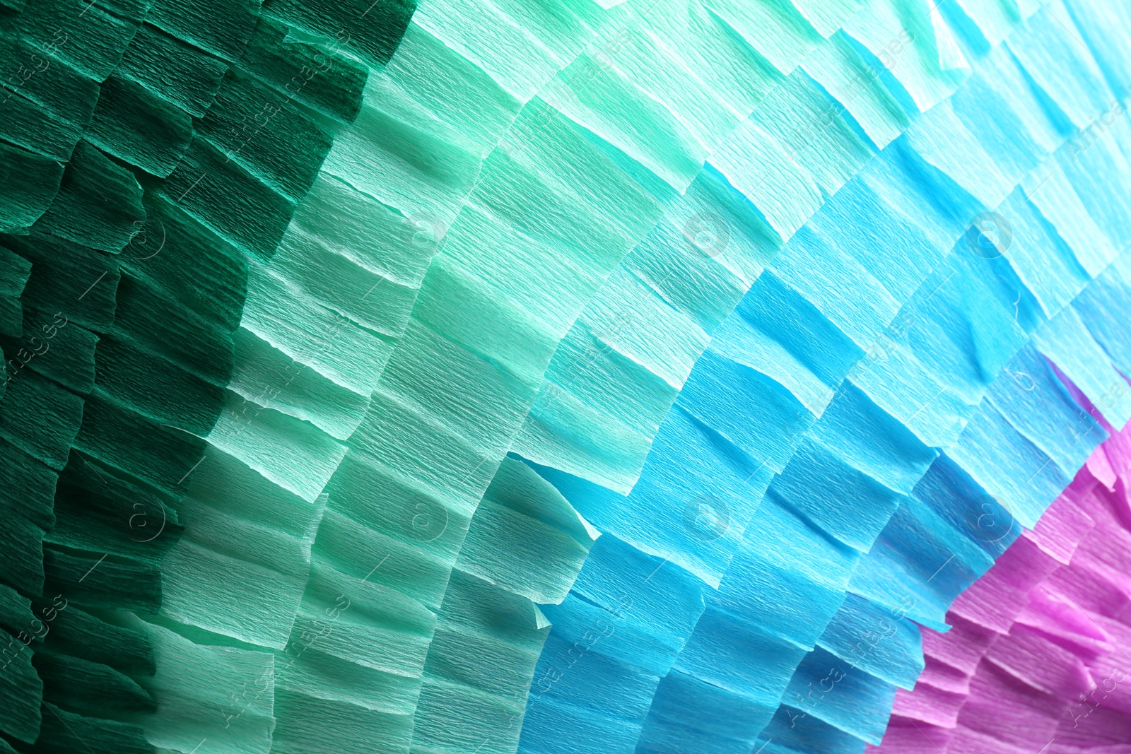 Photo of Pinata. Cut tissue paper in different colors as background, closeup