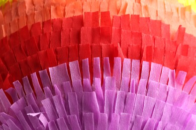 Photo of Pinata. Cut tissue paper in different colors as background, closeup