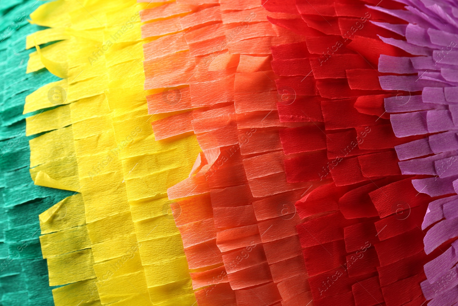 Photo of Pinata. Cut tissue paper in different colors as background, closeup