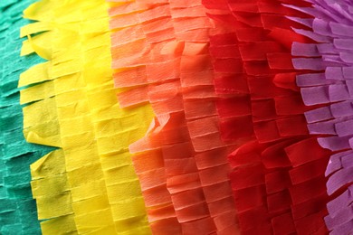 Photo of Pinata. Cut tissue paper in different colors as background, closeup