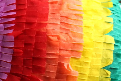 Photo of Pinata. Cut tissue paper in different colors as background, closeup