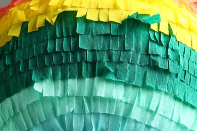 Photo of Pinata. Cut tissue paper in different colors as background, closeup