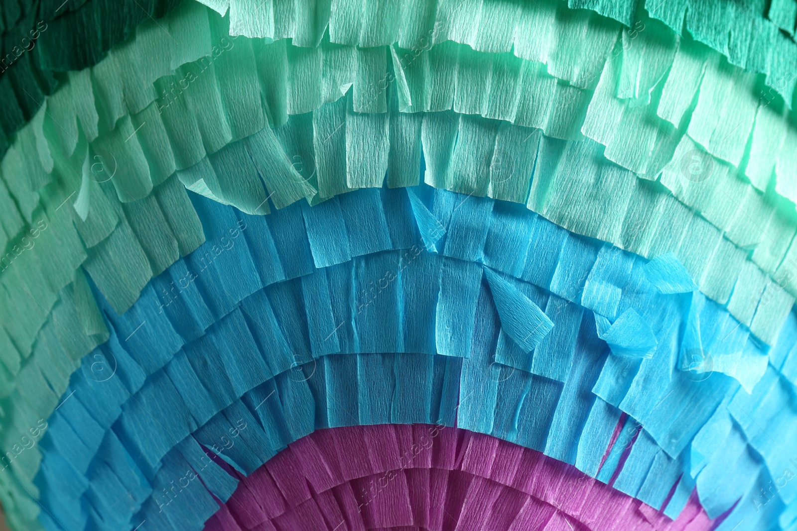 Photo of Pinata. Cut tissue paper in different colors as background, closeup