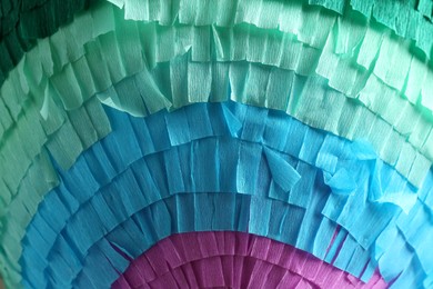 Photo of Pinata. Cut tissue paper in different colors as background, closeup