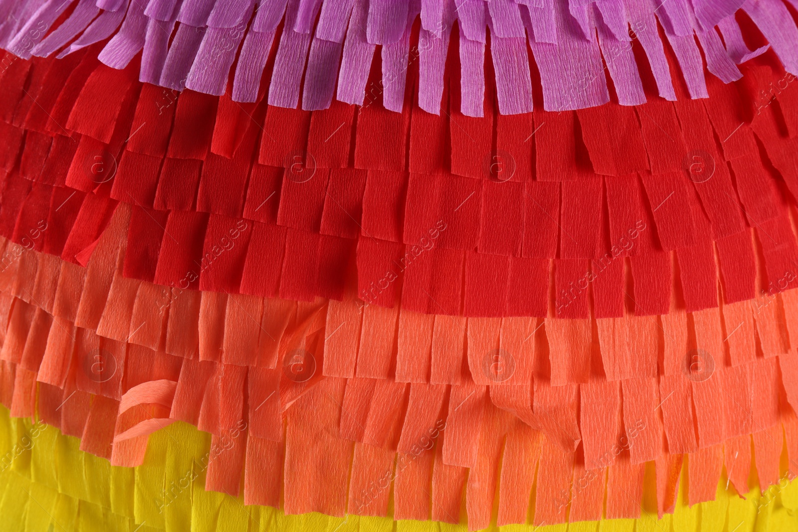 Photo of Pinata. Cut tissue paper in different colors as background, closeup