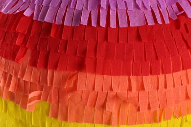 Photo of Pinata. Cut tissue paper in different colors as background, closeup