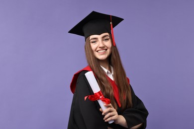 Photo of Happy student with diploma after graduation on violet background