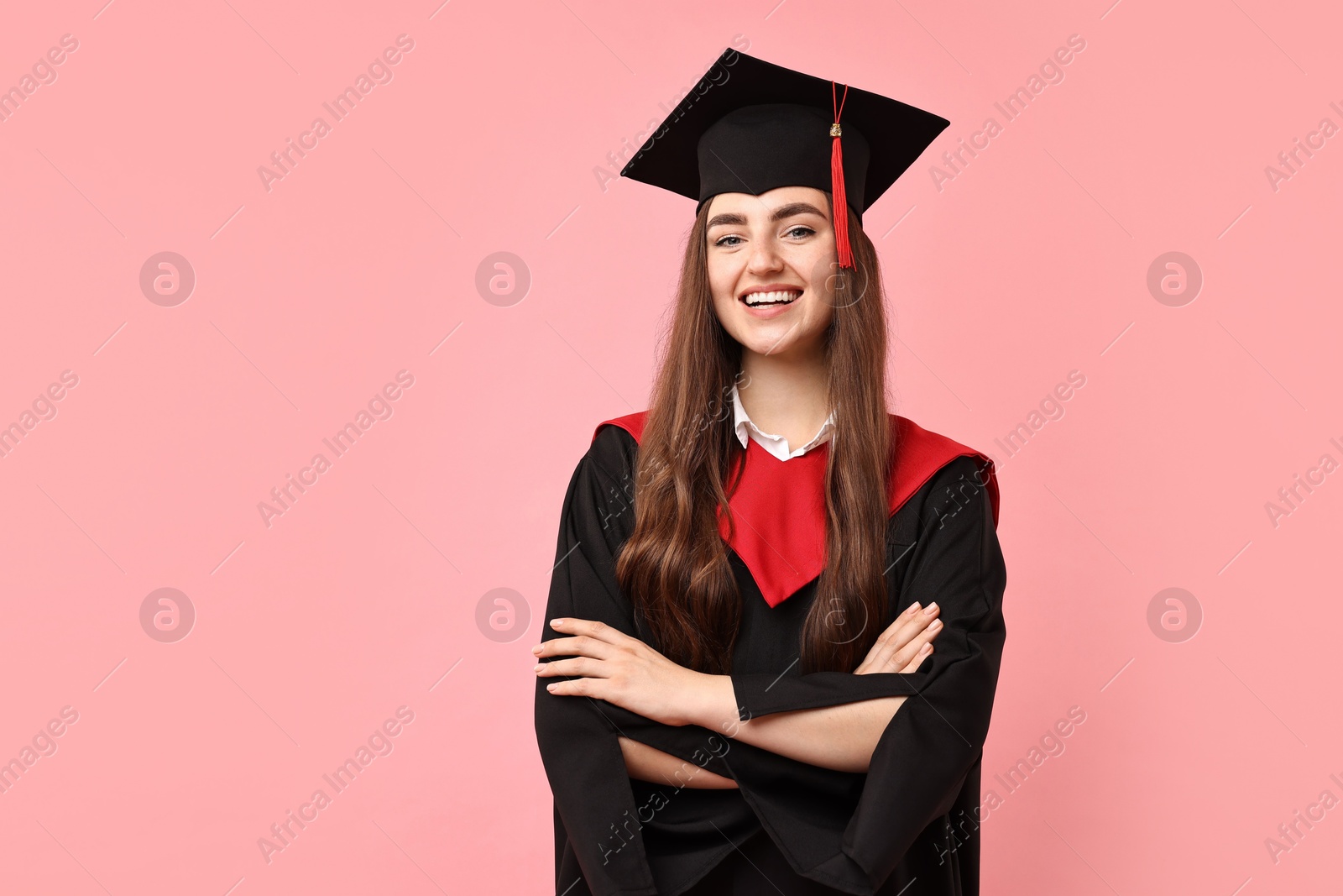 Photo of Happy student with crossed arms after graduation on pink background. Space for text