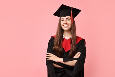 Photo of Happy student with crossed arms after graduation on pink background. Space for text