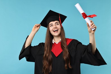 Photo of Happy student with diploma after graduation on light blue background