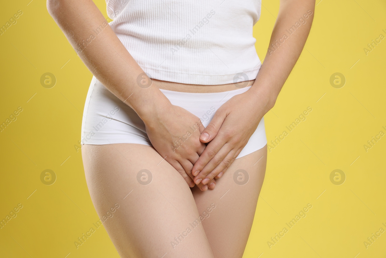 Photo of STD (sexually transmitted disease). Woman suffering from symptoms on yellow background, closeup