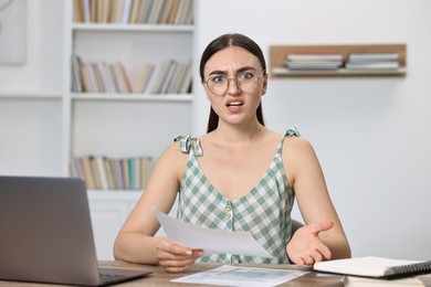 Photo of Emotional student having stress before exam at table indoors