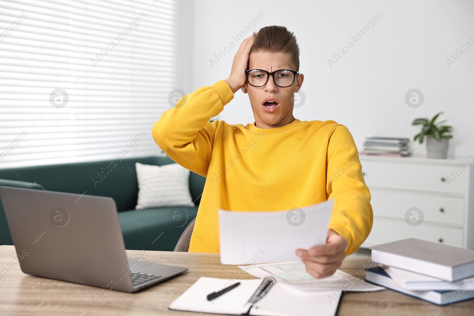 Photo of Emotional student having stress before exam at table indoors