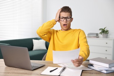 Photo of Emotional student having stress before exam at table indoors