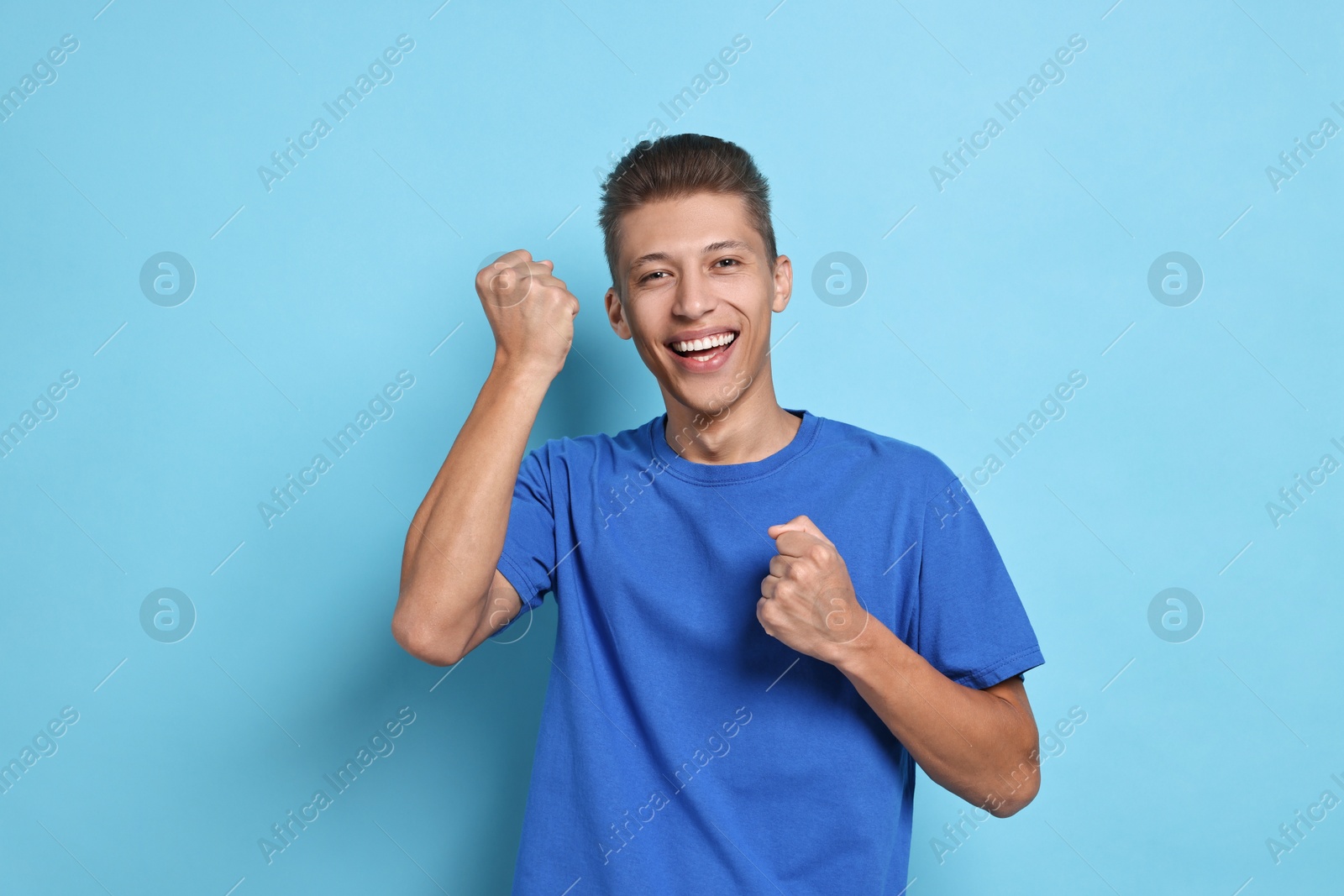 Photo of Student feeling happy about his good exam result on light blue background