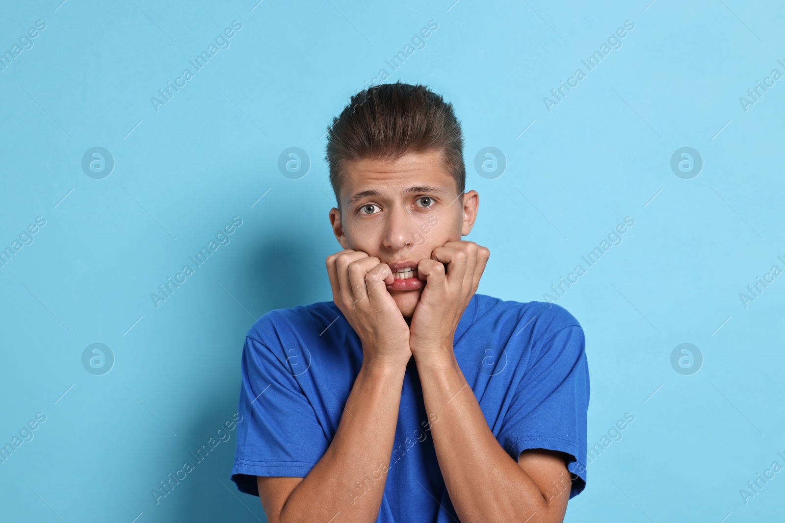 Photo of Emotional student having stress before exam on light blue background