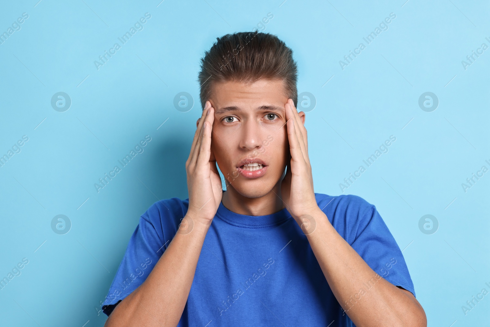 Photo of Emotional student having stress before exam on light blue background