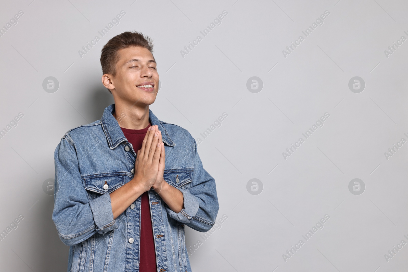 Photo of Student with clasped hands happy about his good exam result on grey background. Space for text