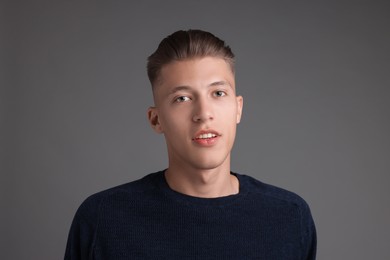 Photo of Handsome young man with stylish haircut on grey background