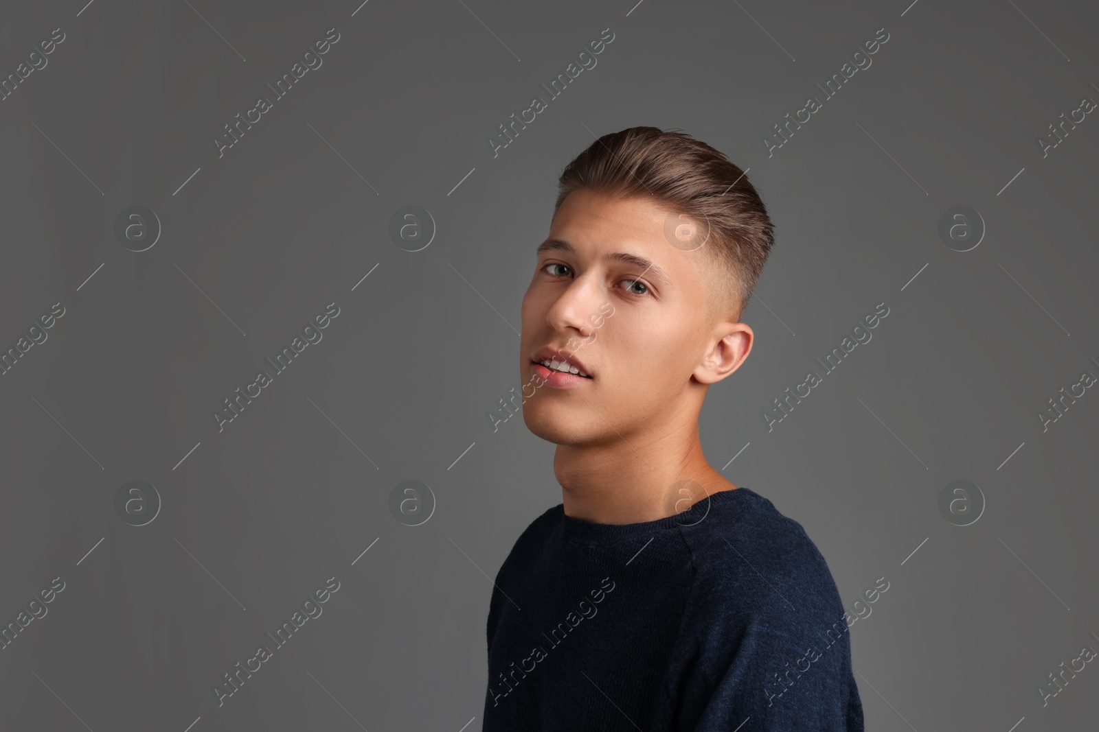 Photo of Handsome young man with stylish haircut on grey background. Space for text