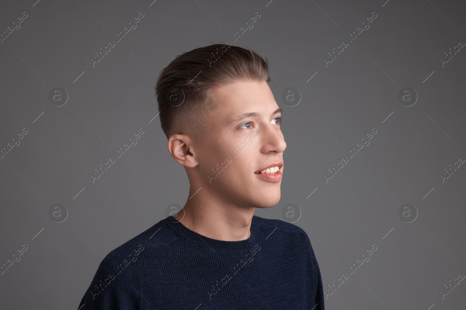 Photo of Handsome young man with stylish haircut on grey background