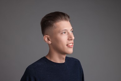 Photo of Handsome young man with stylish haircut on grey background