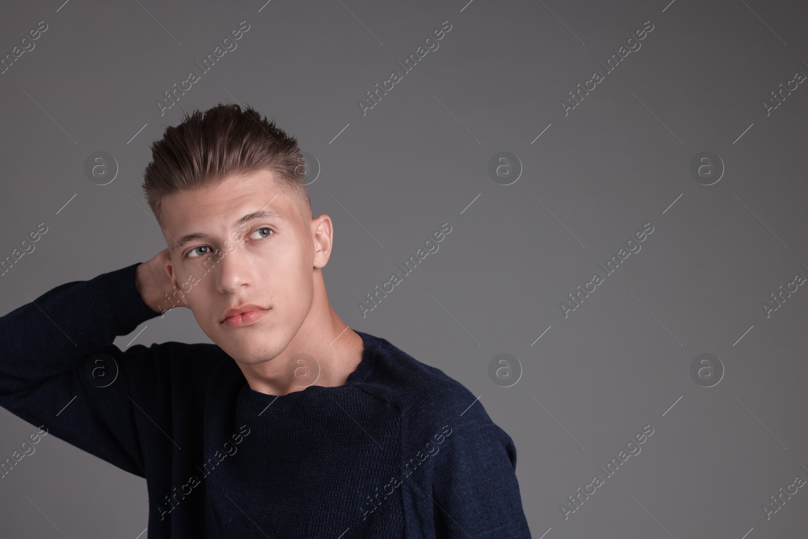 Photo of Handsome young man with stylish haircut on grey background. Space for text