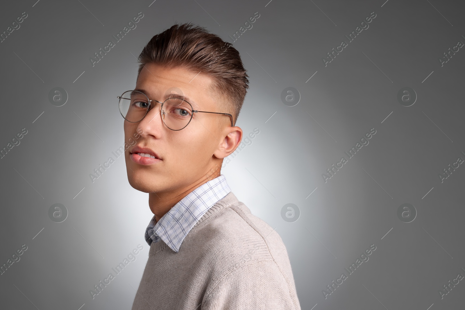 Photo of Handsome young man with stylish haircut on grey background. Space for text