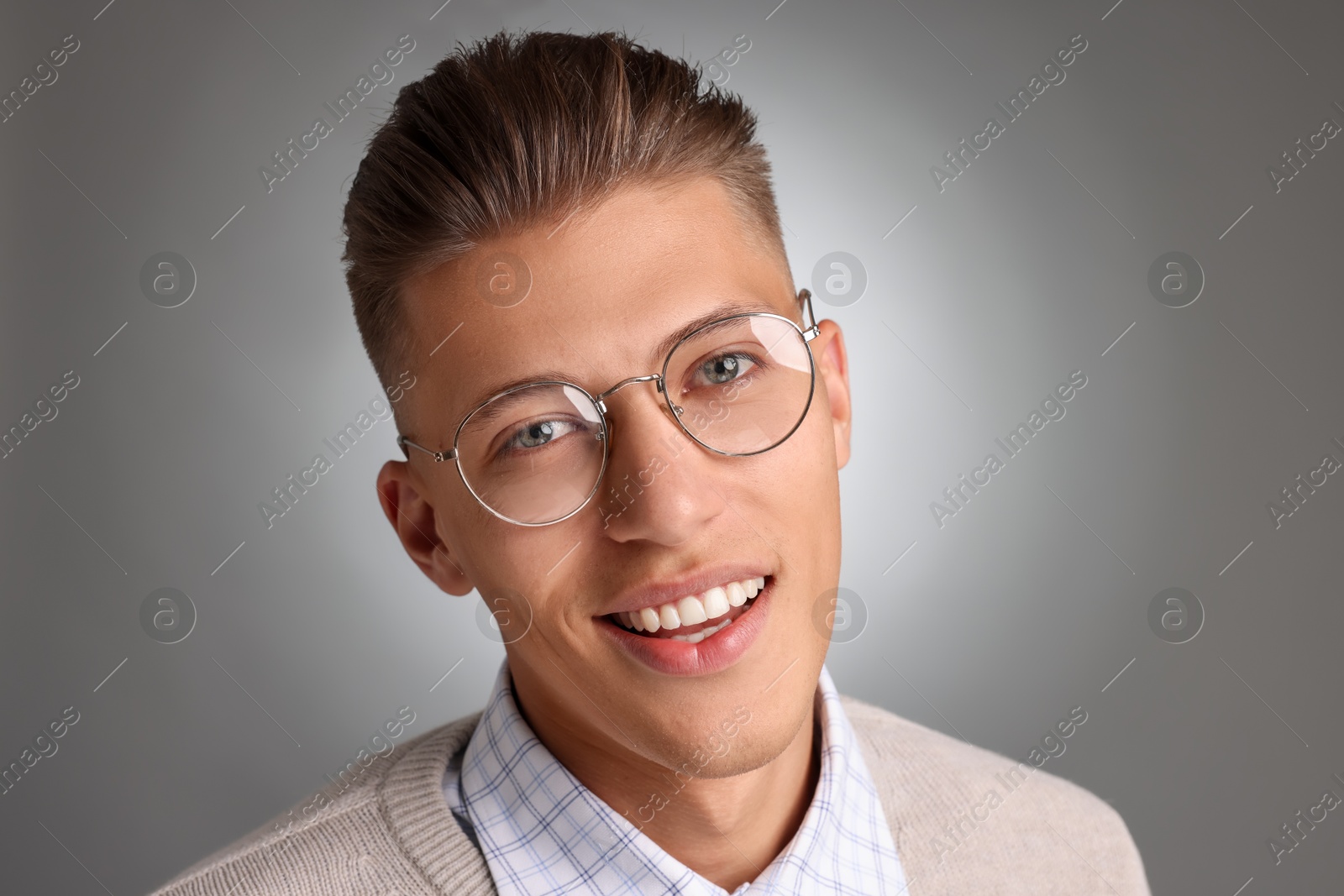 Photo of Handsome young man with stylish haircut on grey background