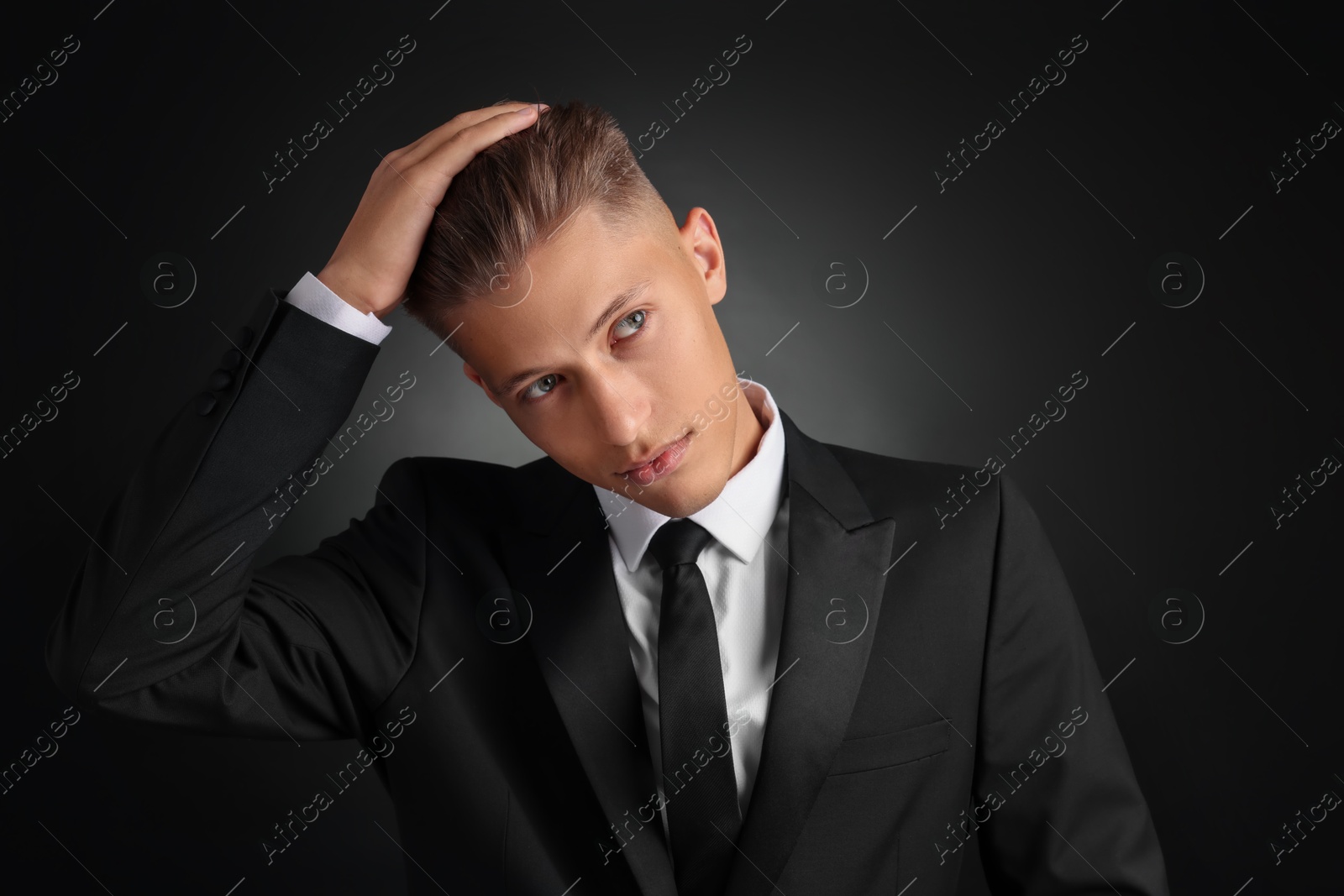 Photo of Confident young man with stylish haircut on black background