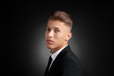 Photo of Confident young man with stylish haircut on black background