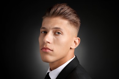 Photo of Confident young man with stylish haircut on black background